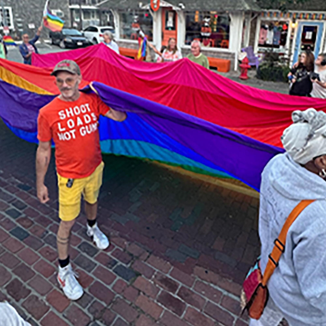 Adam Singer protesting in Provincetown outside Adam's Nest, wearing an orange "Shoot loads not guns" tee supporting Gays Against Guns