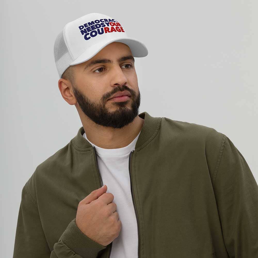 Man wearing a white cap and green jacket against a plain background