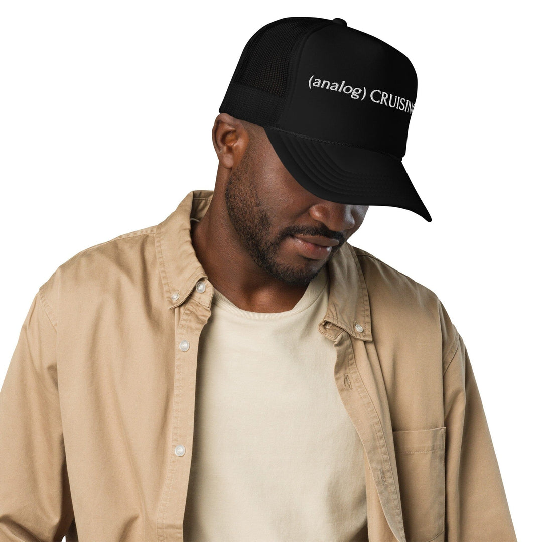Male model wearing black (analog) CRUISING foam trucker hat with white embroidery, right front view, Adam&