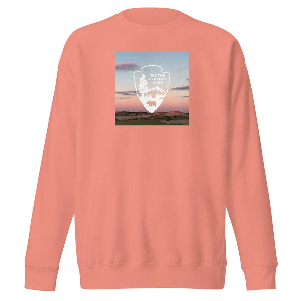Peach-colored sweatshirt with a graphic design on the chest against a white background