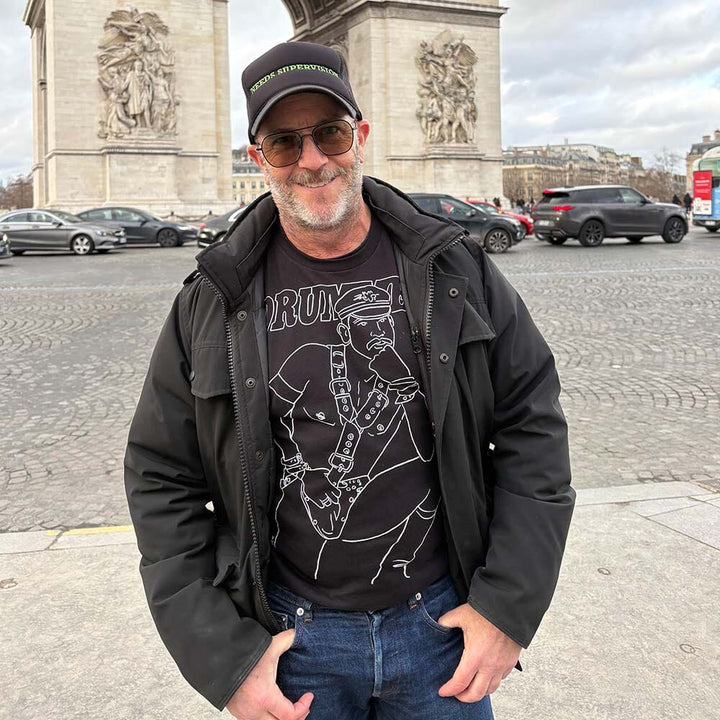 Man standing in front of a historical monument with cars and people in the background