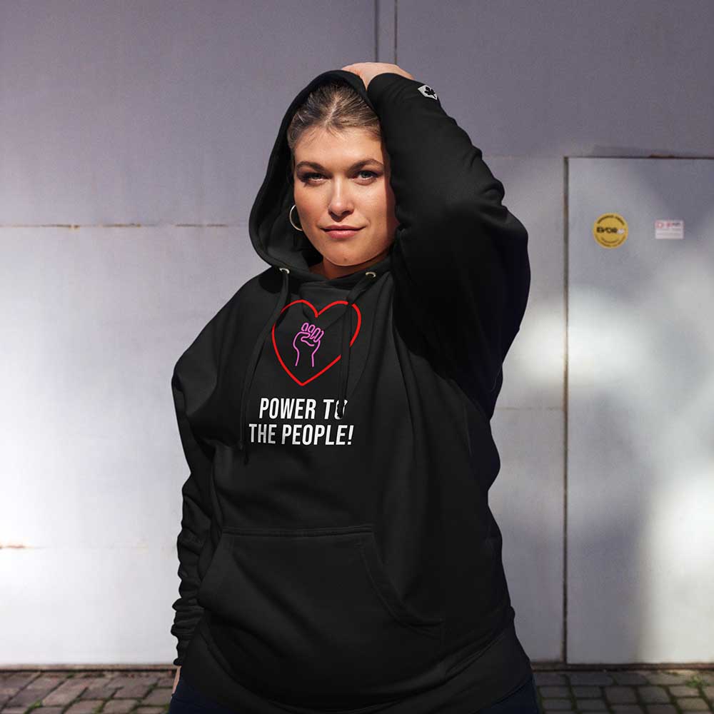 Person wearing a black hoodie with a heart and text design, standing against a wall.