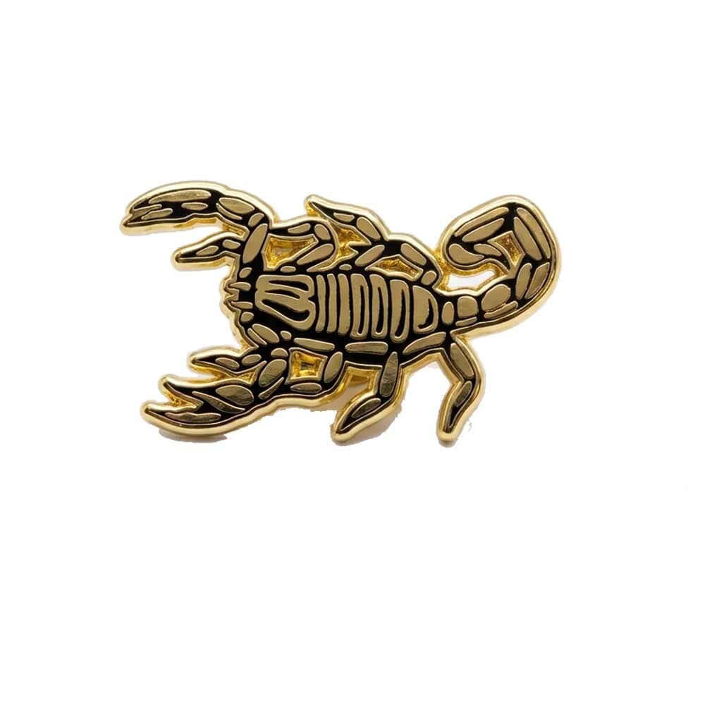 Gold scorpion-shaped pin on a white background
