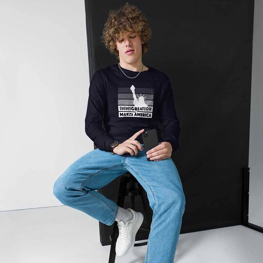 Person wearing a black long-sleeve t-shirt with a graphic of the statue of liberty that reads immigration makes America on a white background.