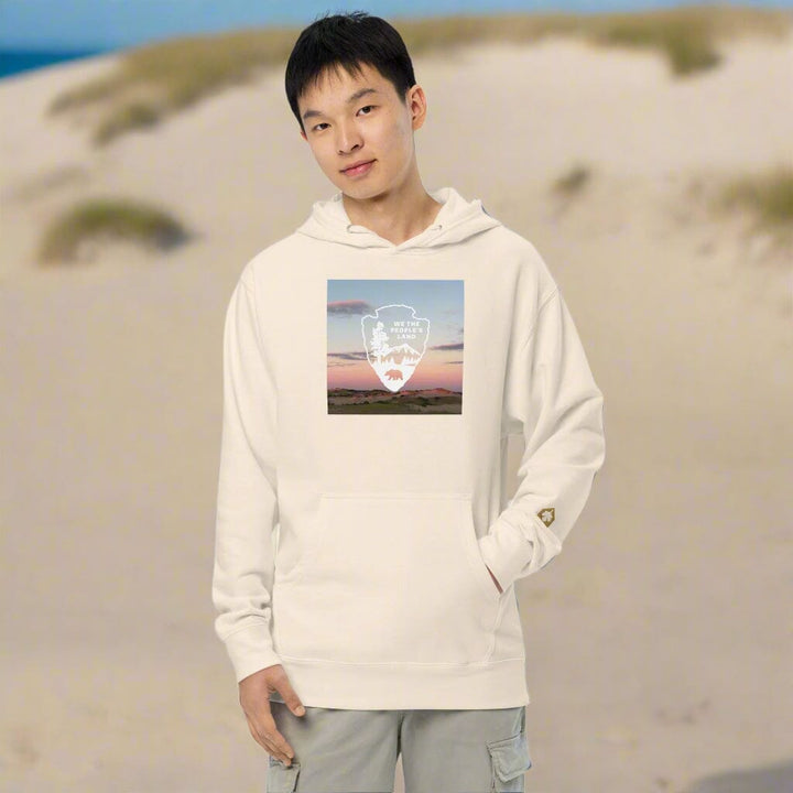 Person wearing a cream hoodie with a graphic design on a white background