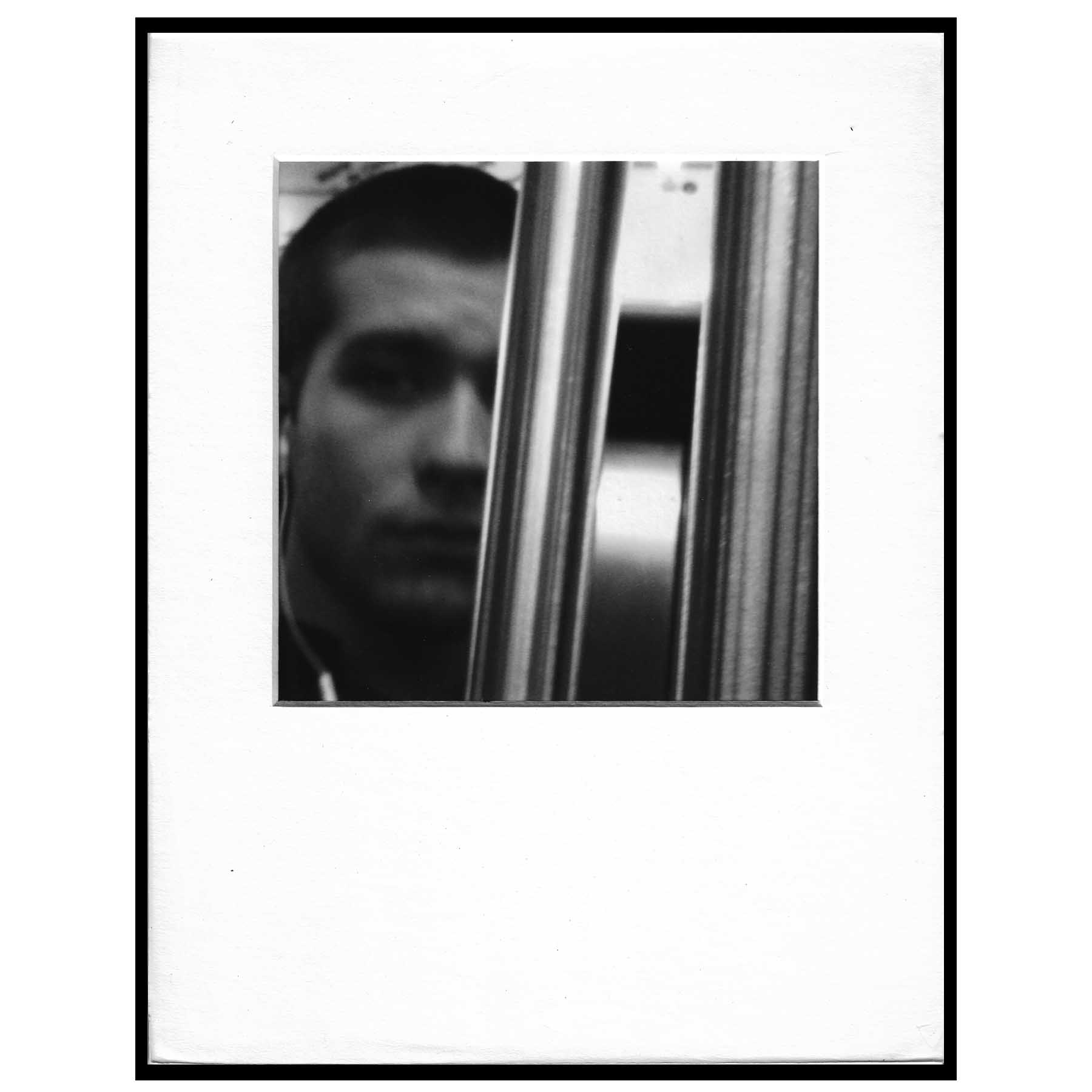 black and white photo of a pole obscuring a man's face